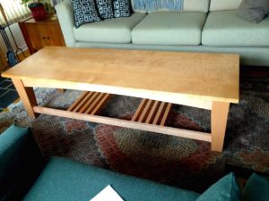 #2023 coffee table.  This lovely coffee table has a base made of Maple and the table top is curly Maple.   66” x 22” x 18”h Finish is a warm light brown stain and a durable stain lacquer for table tops